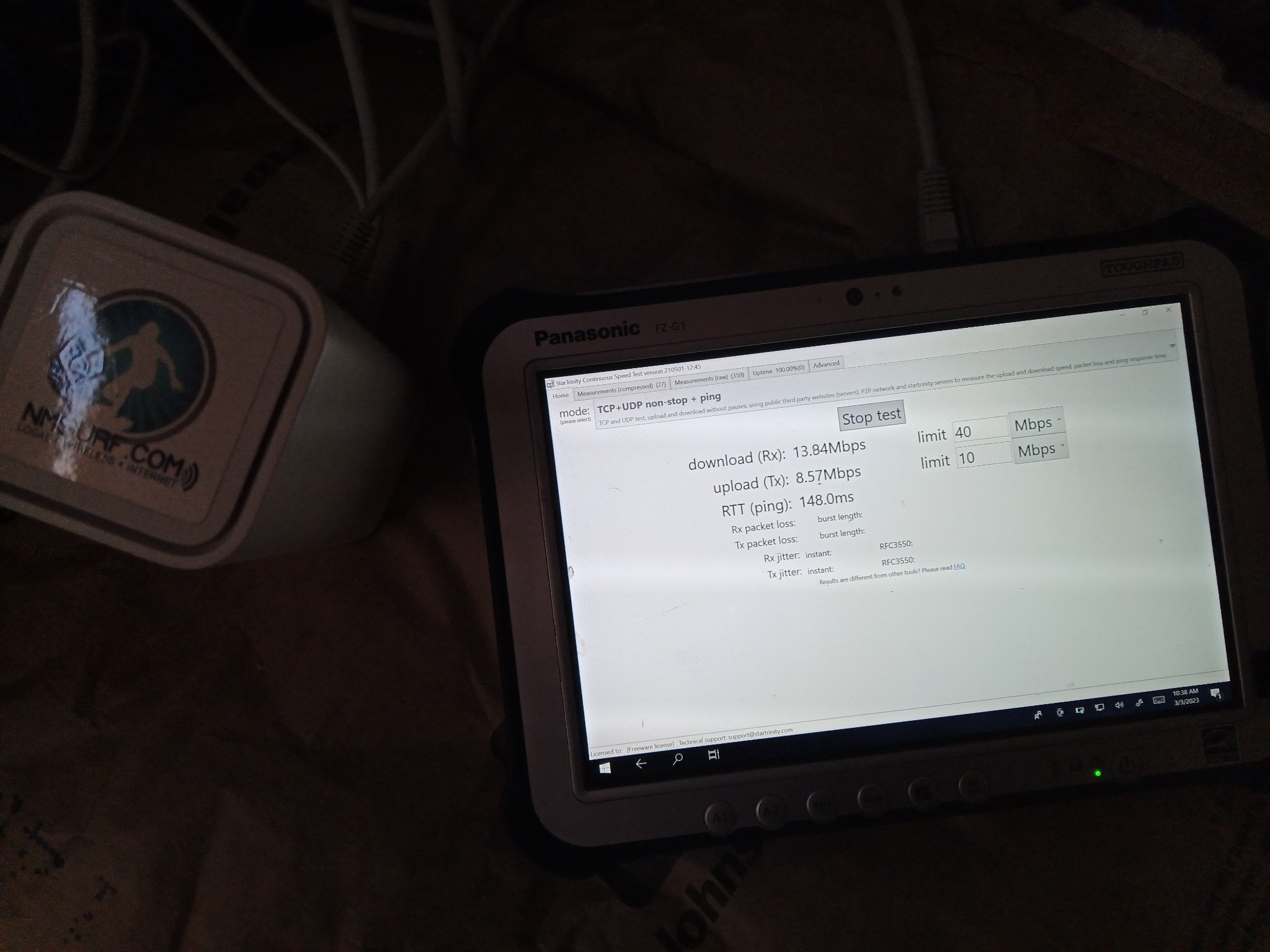 Technician laptop running a continuous internet test beside ISP modem equipment